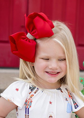 Girl wearing a red 5.5 inch oversize rhinestone center knot hair bow