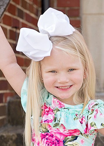 Girl wearing a white 5.5 inch oversize rhinestone center knot hair bow