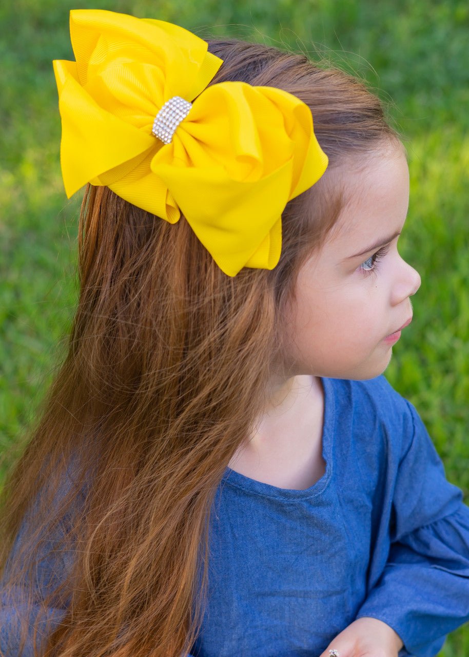 Girl wearing a yellow 5.5 inch oversize rhinestone center knot hair bow
