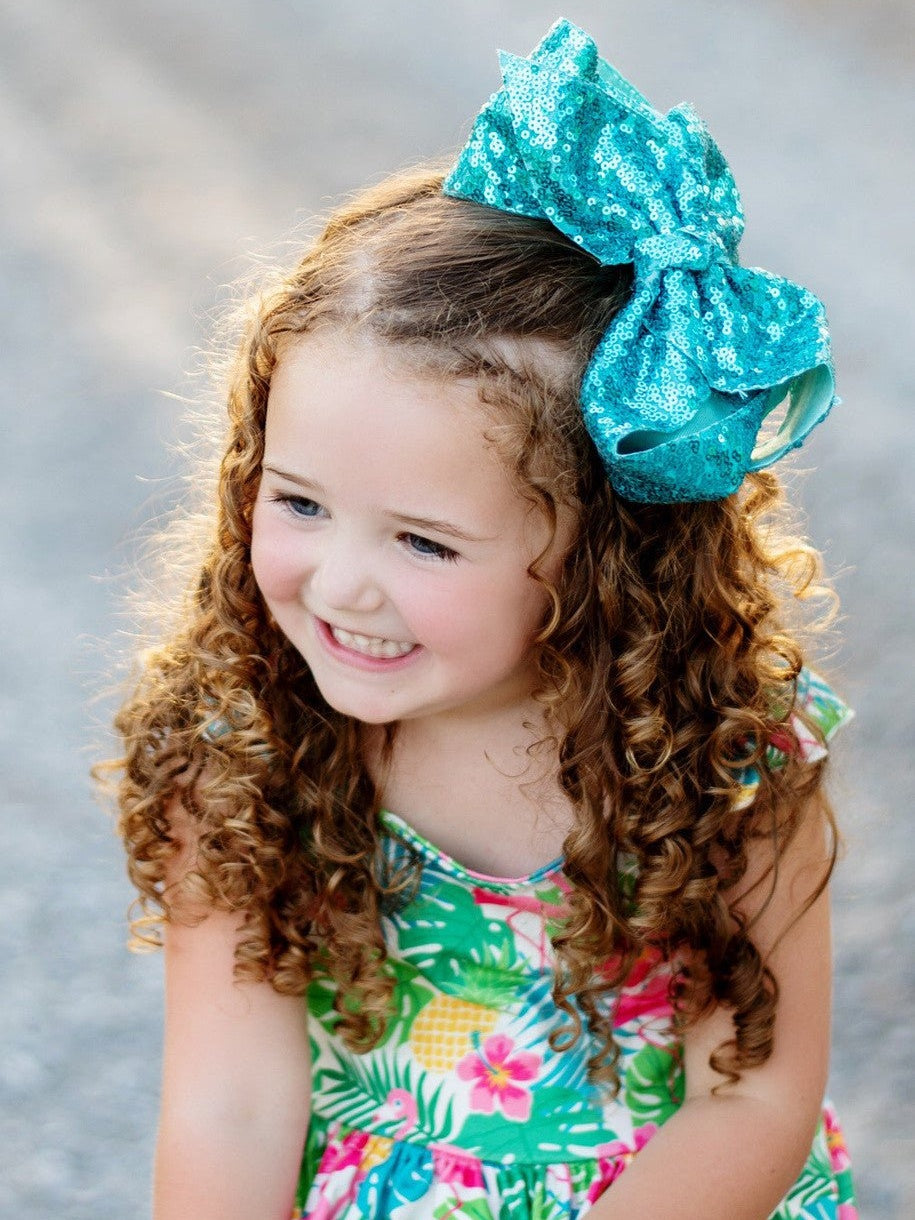 Girl wearing 6.5 inch turquoise sequin Texas size hair bow