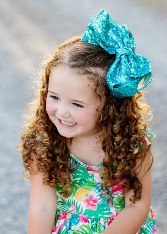 Girl wearing 6.5 inch turquoise sequin Texas size hair bow
