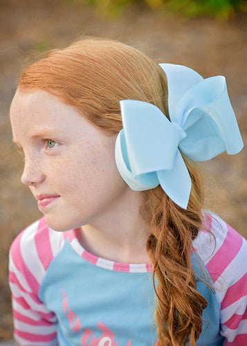 Girl wearing a sky blue 6.5 inch Texas size grosgrain hair bow