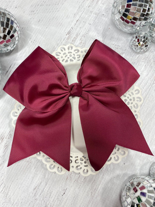 Maroon cheer bow on wood background