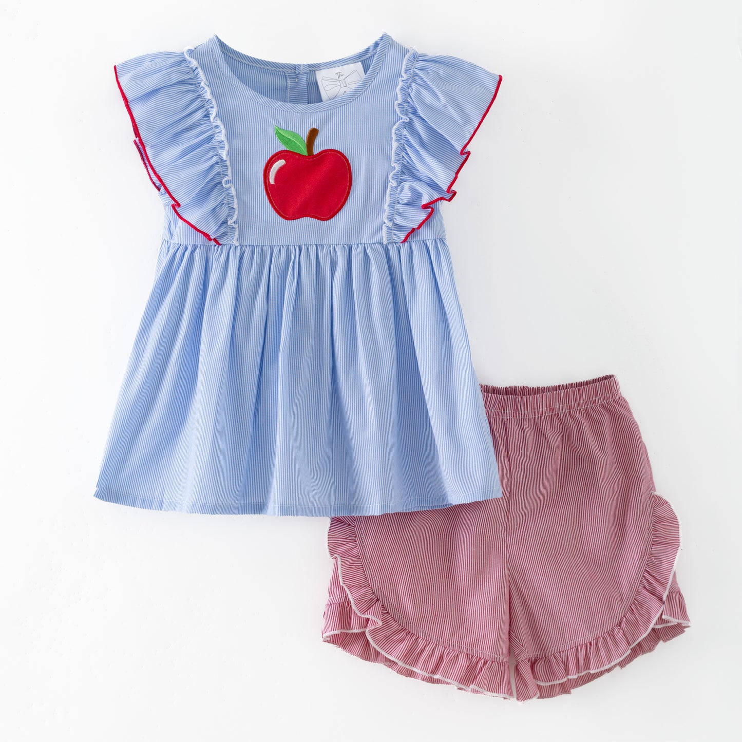 Children's outfit with blue top and pink shorts featuring an apple design on a white background