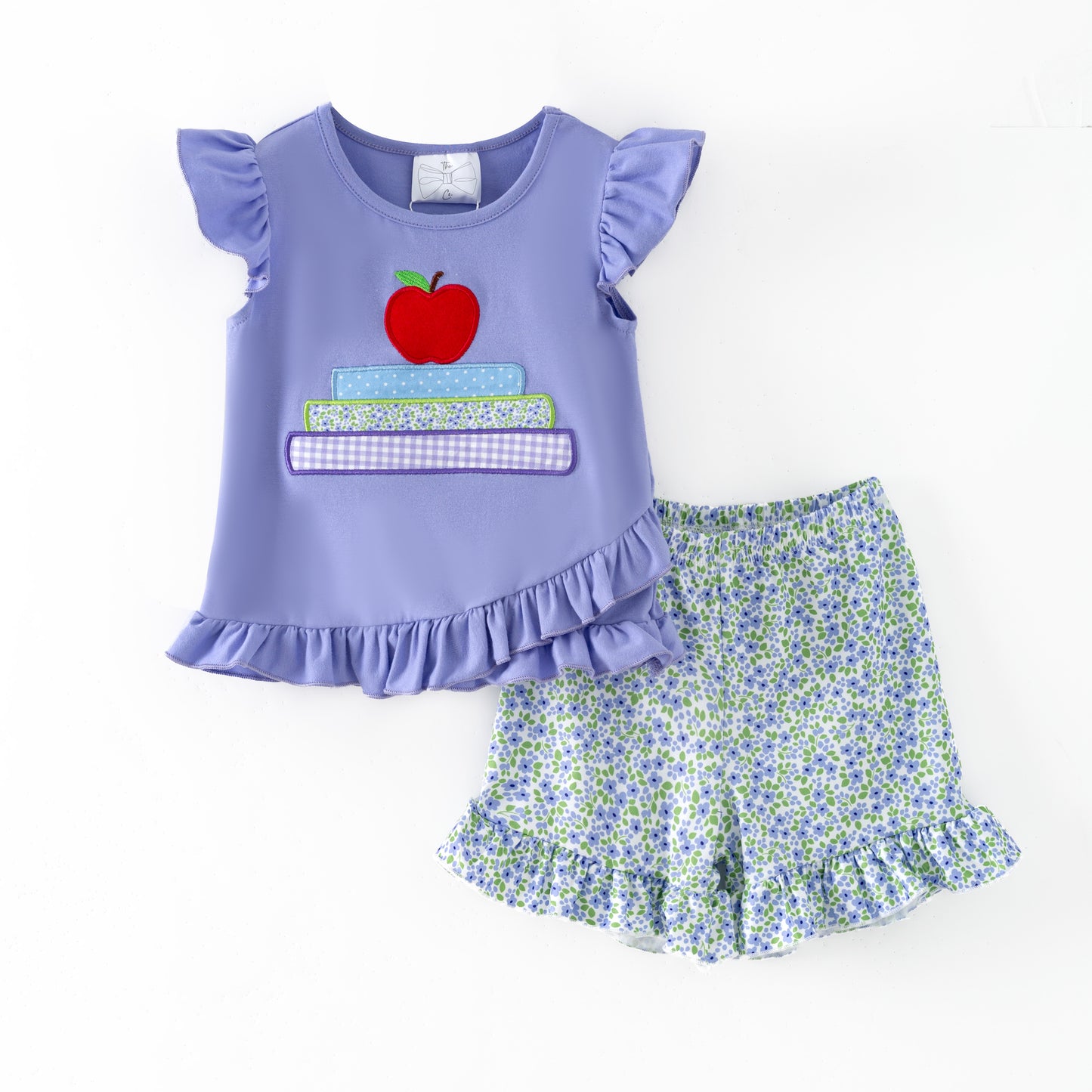 Children's outfit with purple top and floral shorts on a white background