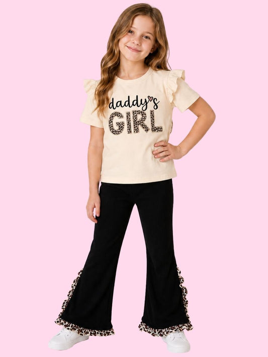 Girl wearing a 'daddy's girl' shirt with ruffled sleeves & pants on a pink background