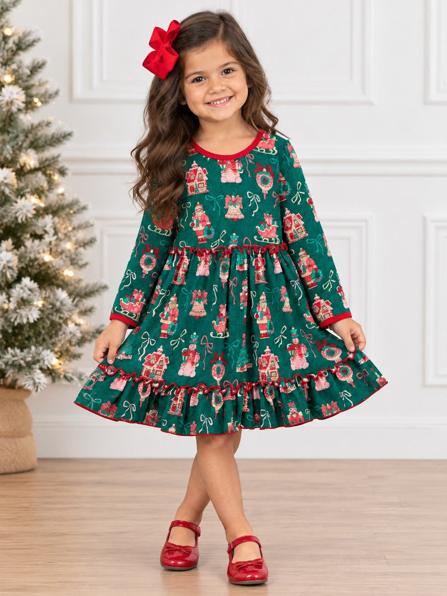 Girl wearing a Girls Vintage Christmas Print Ruffle Twirl Dress in green with festive holiday prints, red trim, and a ruffled hem, standing beside a Christmas tree.