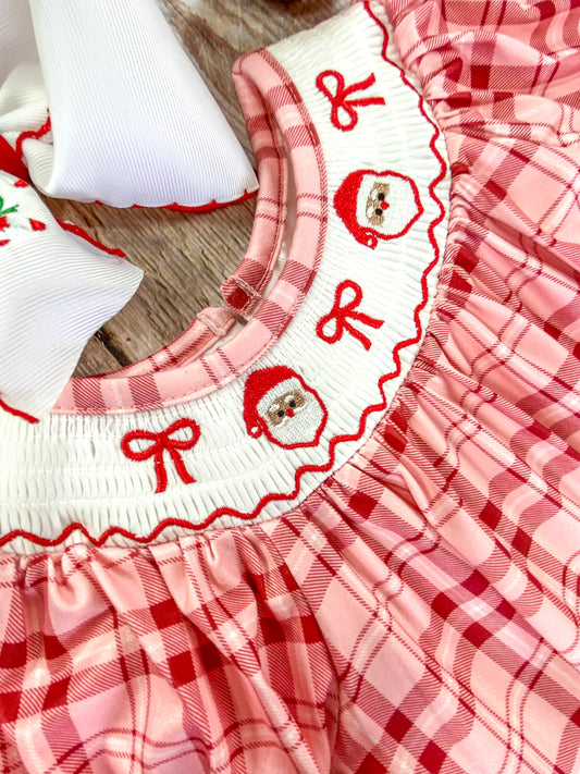 Close-up of a white smocked collar on an infant romper, embroidered with 2 Santa Claus faces and 3 red bows. The detailed stitching emphasizing the festive and delicate craftsmanship. - Alternative view