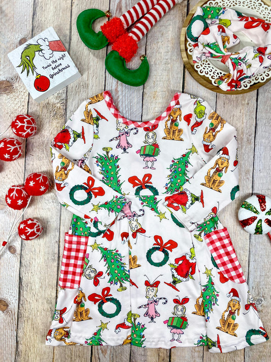 Girls’ long sleeve Christmas twirl dress featuring an all-over Grinch character print on white, with red and white gingham-trimmed pockets and matching neckline. Made from soft, stretchy knit fabric and cut for a twirl-friendly silhouette—perfect for holiday parties and photos. - Alternative view