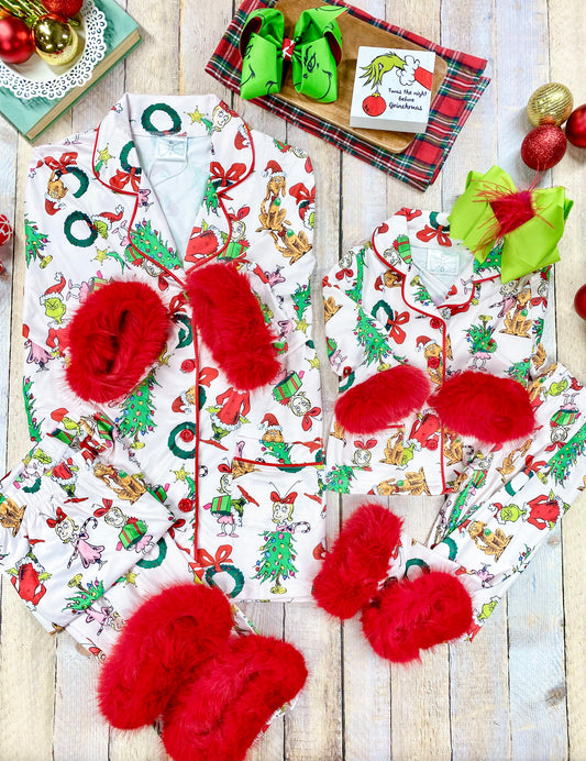 Matching mommy and me two-piece Christmas pajamas with a festive white background and colorful Grinch-themed character print, including Max the dog, Cindy Lou Who, and the Grinch. Each pajama set includes a collared button-up top and long pants with bright red faux fur trim on the cuffs and hem for a cozy holiday look.