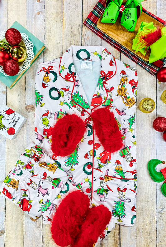 Women’s two-piece Christmas pajama set featuring a Grinch-themed print on white fabric, with red buttons and vibrant red faux fur trim at the wrists and ankles. Includes a long sleeve button-up shirt with chest pocket and matching full-length pants. - Alternative view