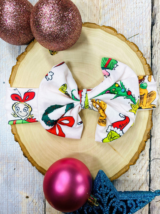  fabric bows with festive designs on a wooden surface with Christmas ornaments.
