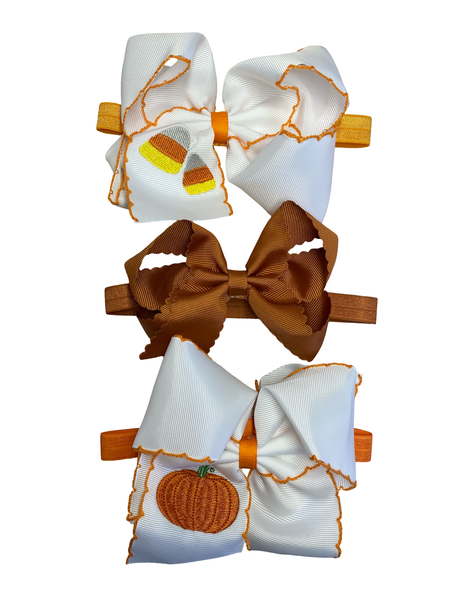 Set of three hair bows with pumpkin designs on a white background on headbands