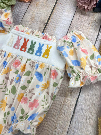 Children's outfit with floral pattern and embroidered bunnies on a wooden surface