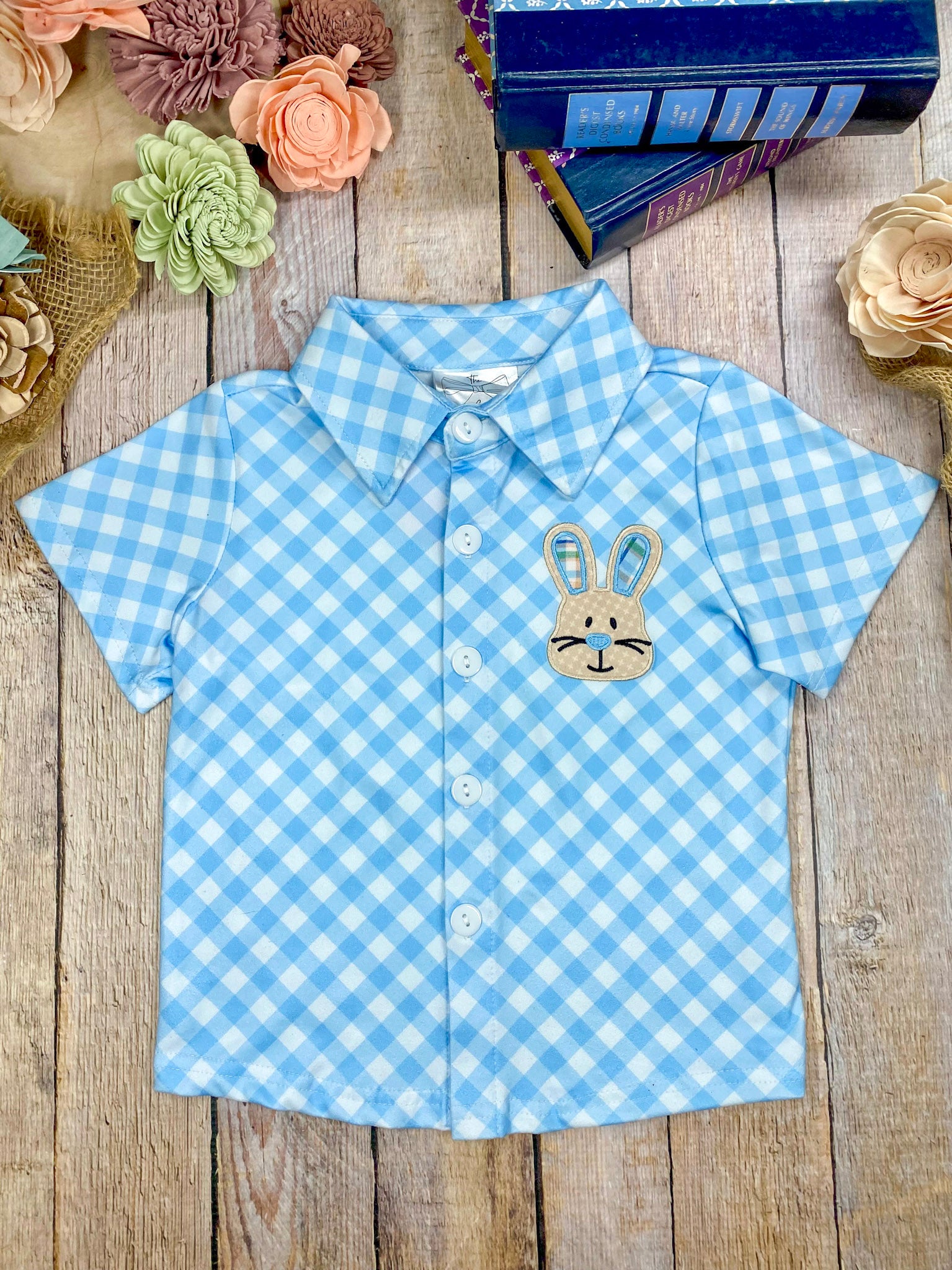 Blue checkered shirt with a bunny design on a wooden surface