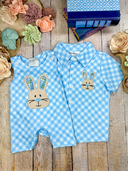 Blue checkered baby romper with bunny design on a wooden surface with flowers. - Alternative view