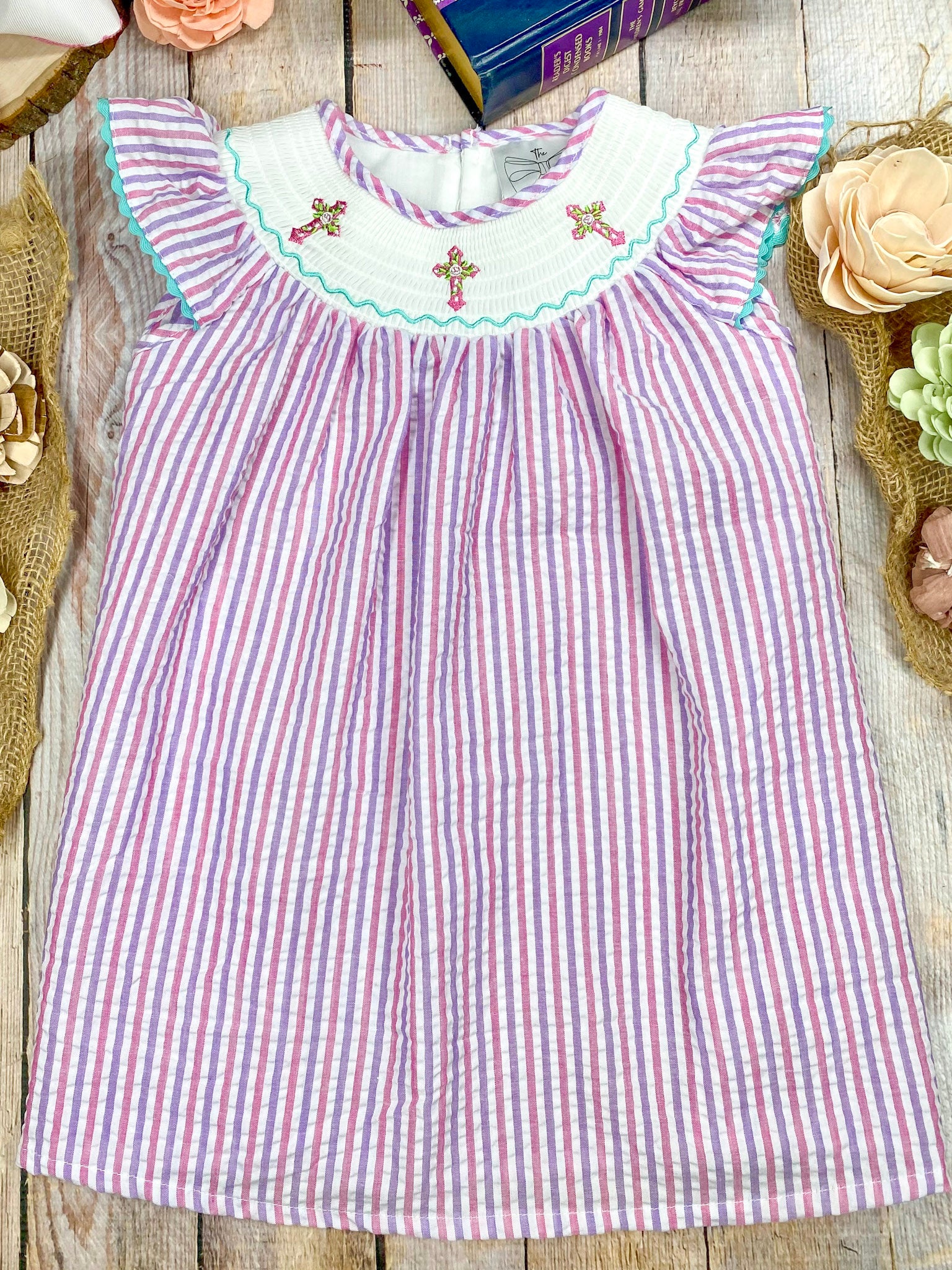 Striped dress with cross embroidered collar on a wooden surface