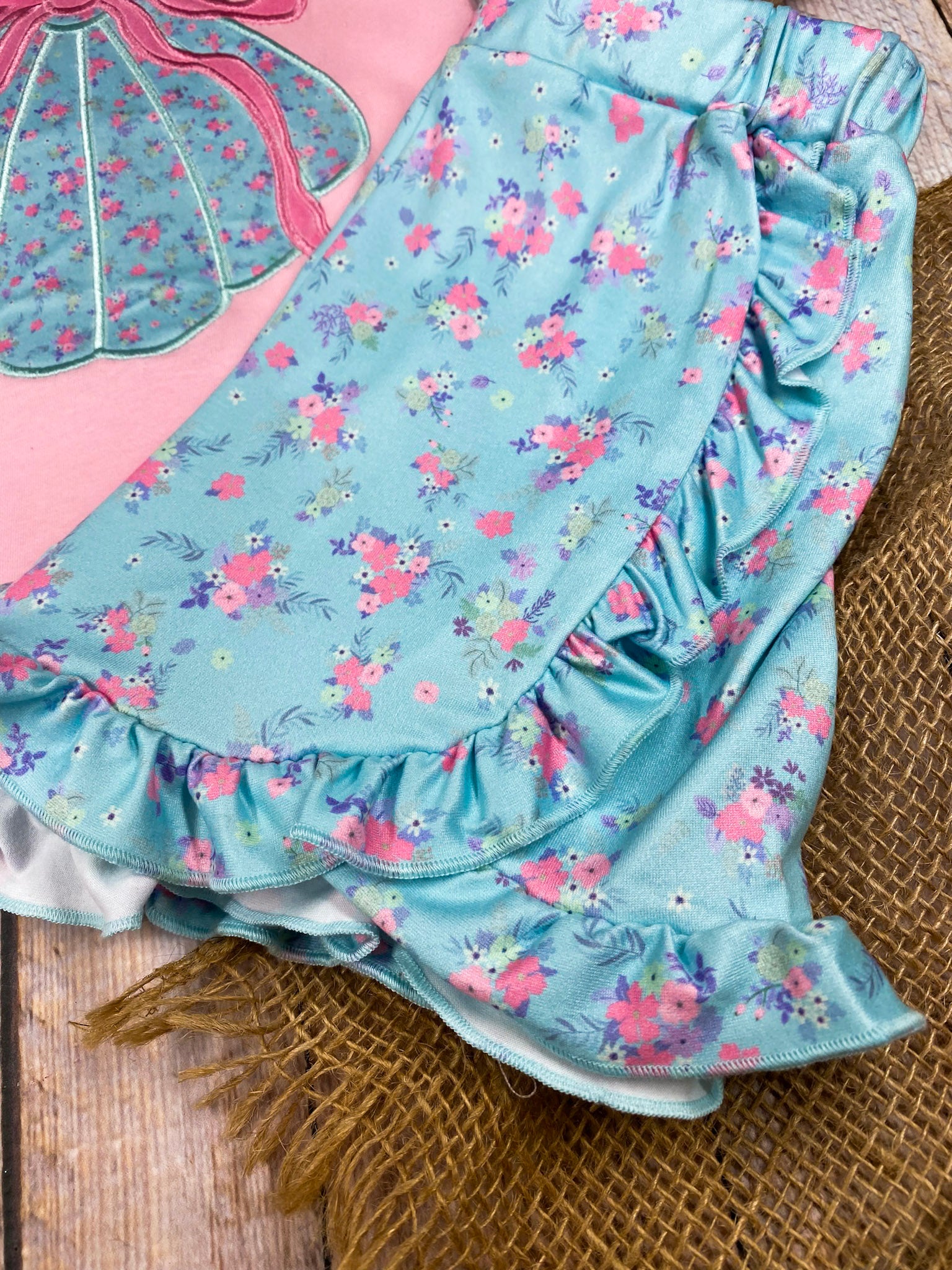 Girls sea shell outfit with pink top and blue shorts on a wooden background