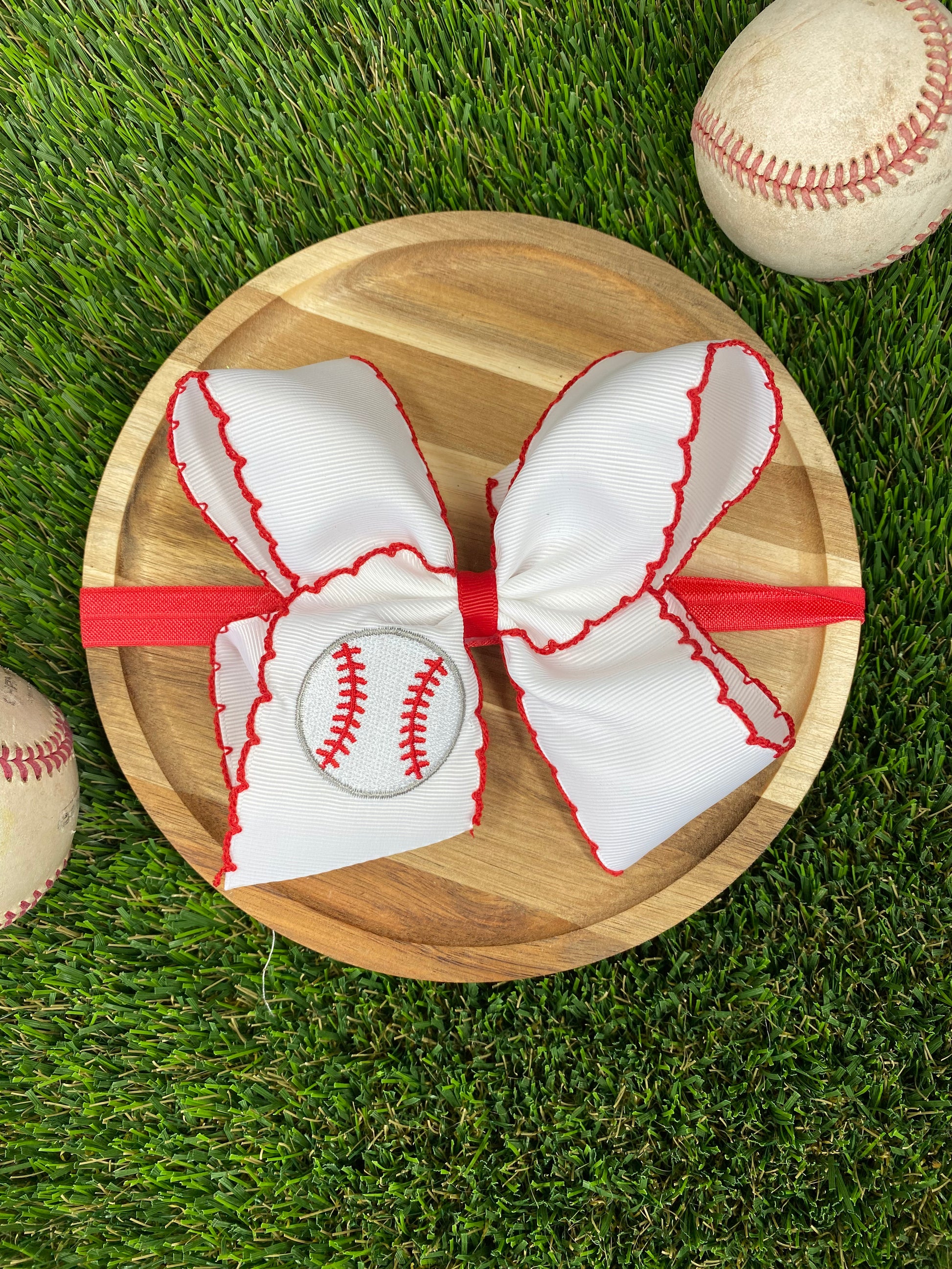 red and white baseball embroidered headband on a grass background