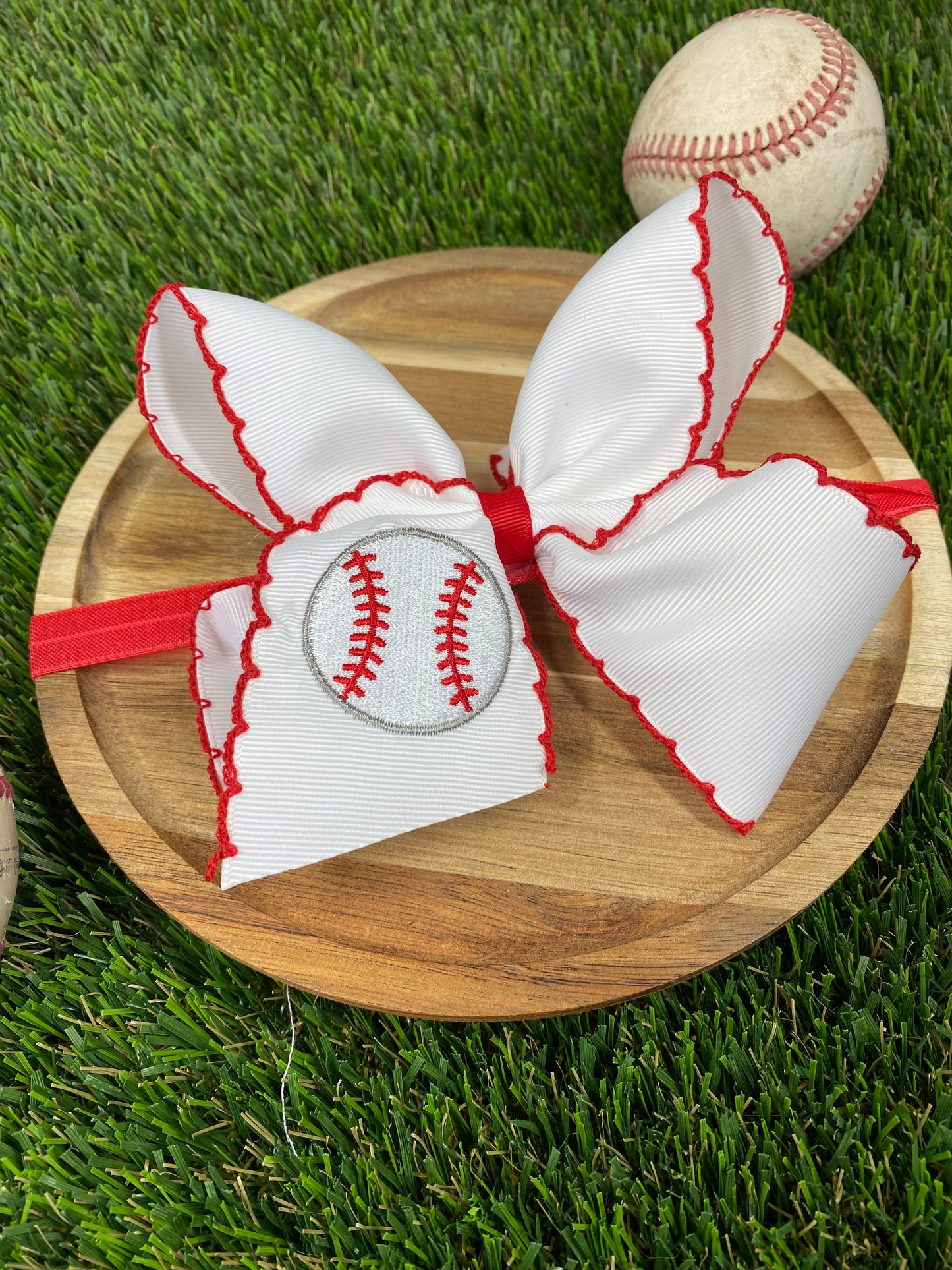 red and white baseball embroidered headband on a grass background
