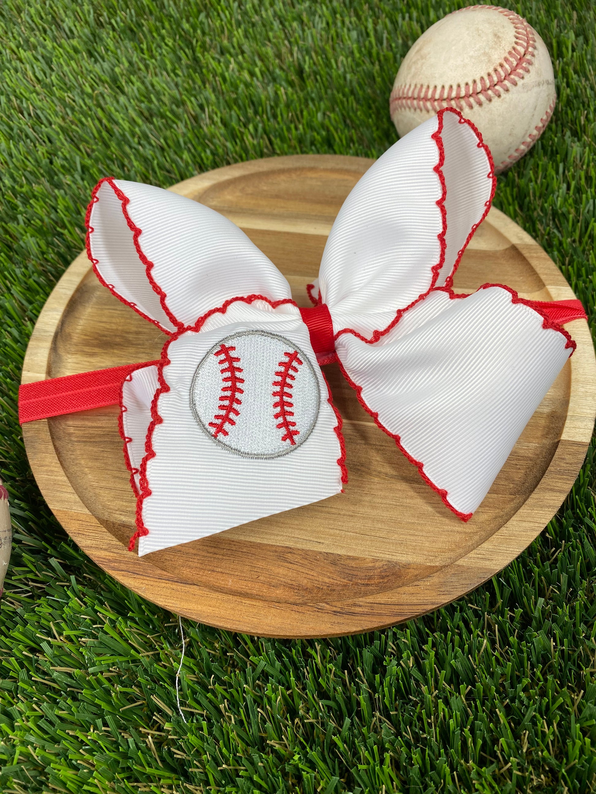 red and white baseball embroidered headband on a grass background