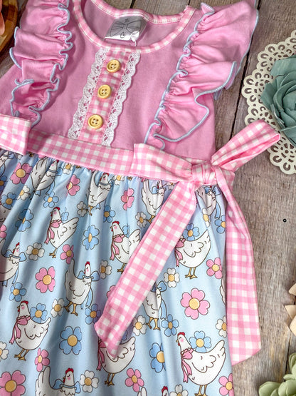Children's dress featuring chicken pattern on a wooden background