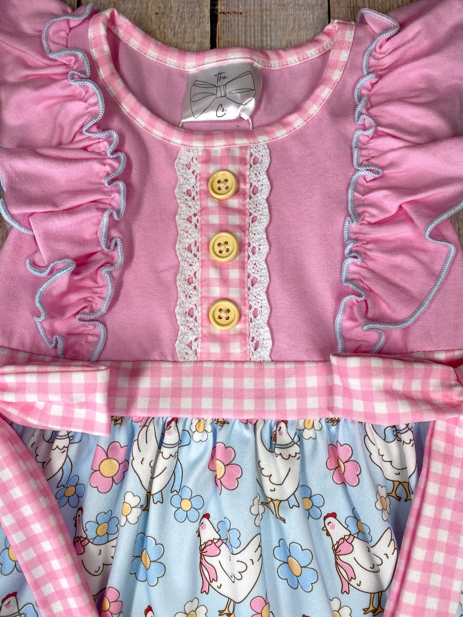 Children's dress featuring chicken pattern on a wooden background