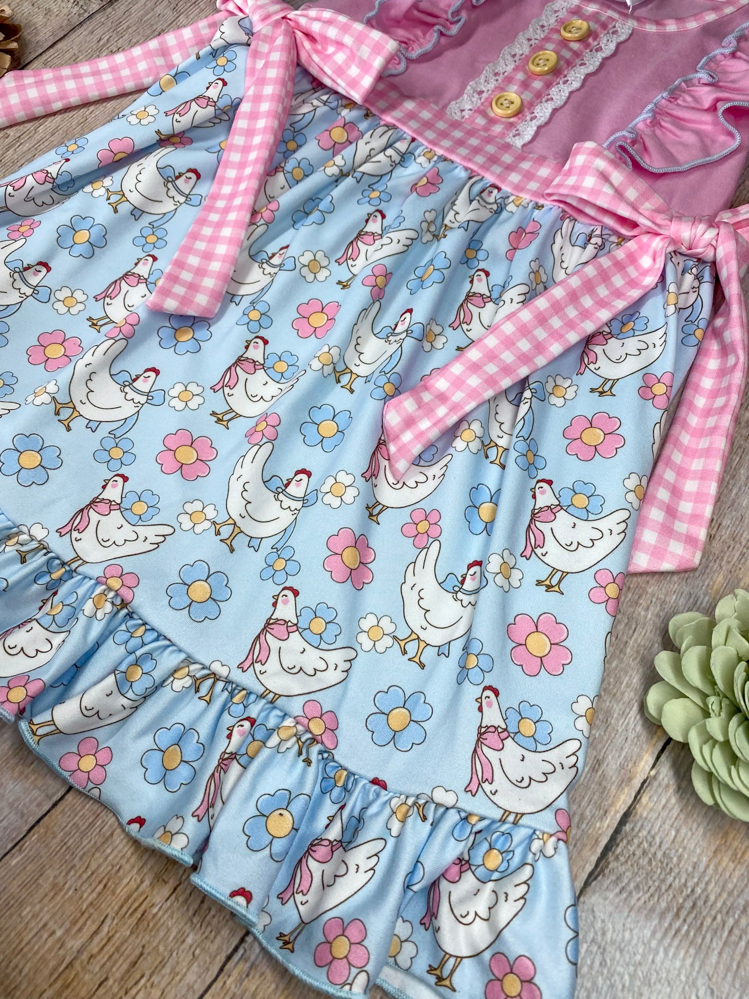 Children's dress featuring chicken pattern on a wooden background