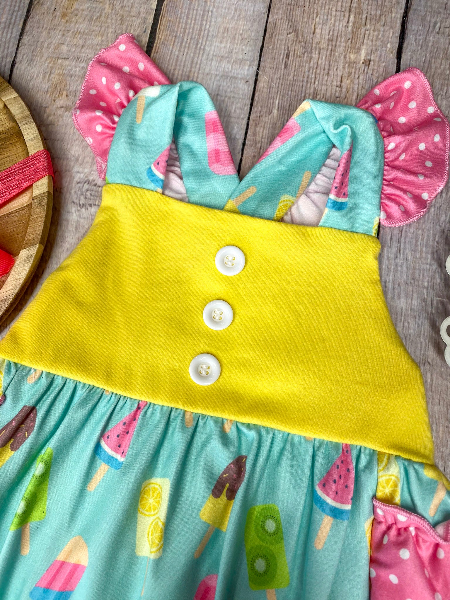 Colorful baby romper with ice cream pattern on a wooden background