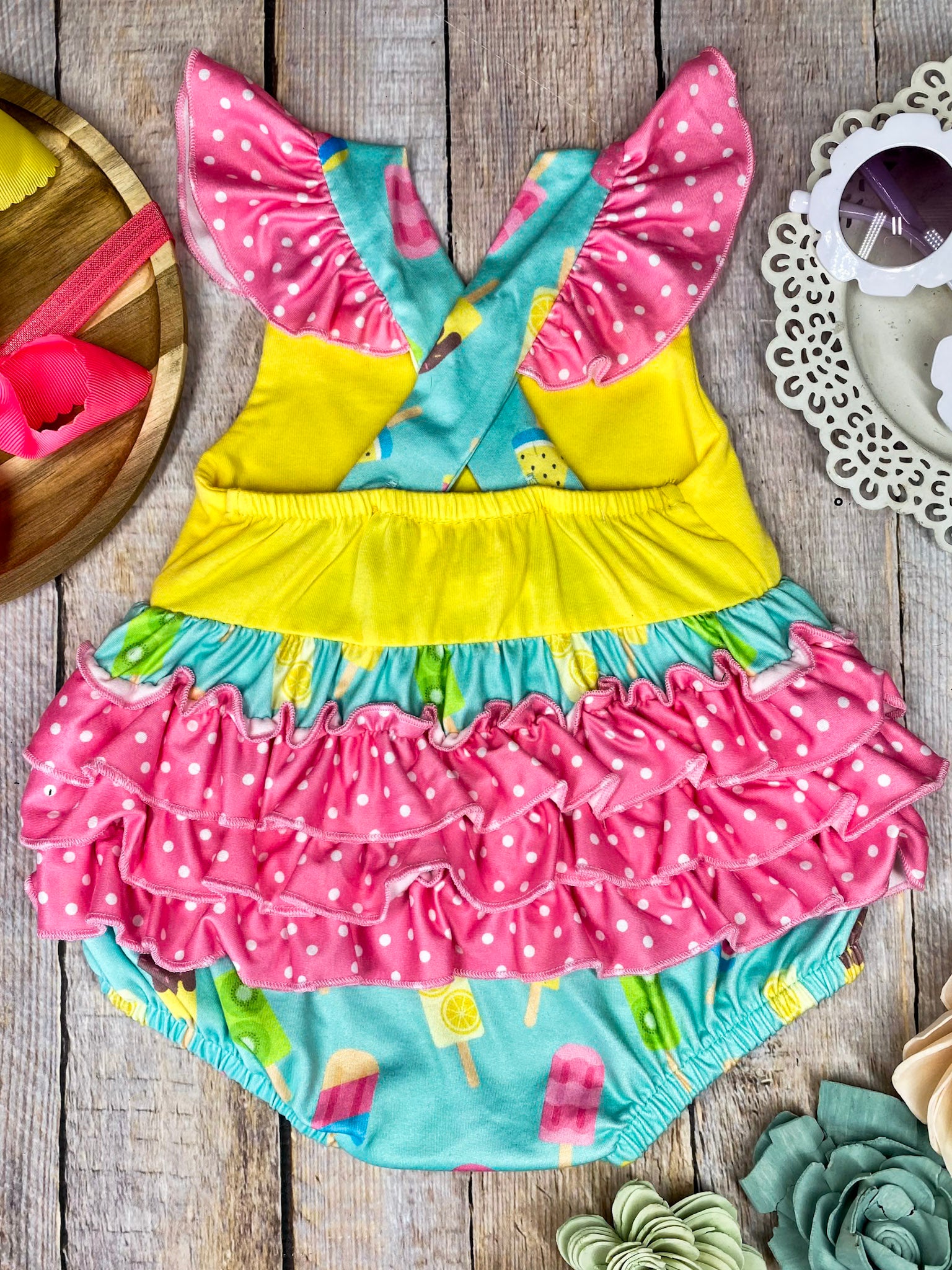 Colorful baby romper with ice cream pattern on a wooden background