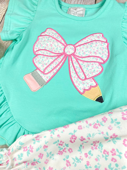 Children's outfit with green pencil top and floral shorts on a wooden background