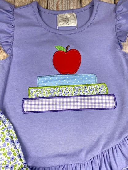 Children's outfit with purple top and floral shorts on a wooden background