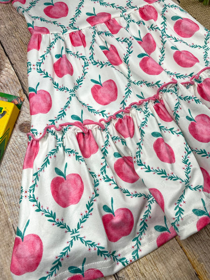 Children's dress with pink apple pattern on a wooden background