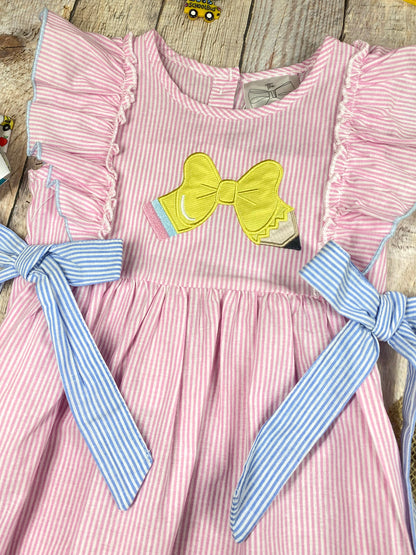 Pink striped dress with a bow on a wooden background