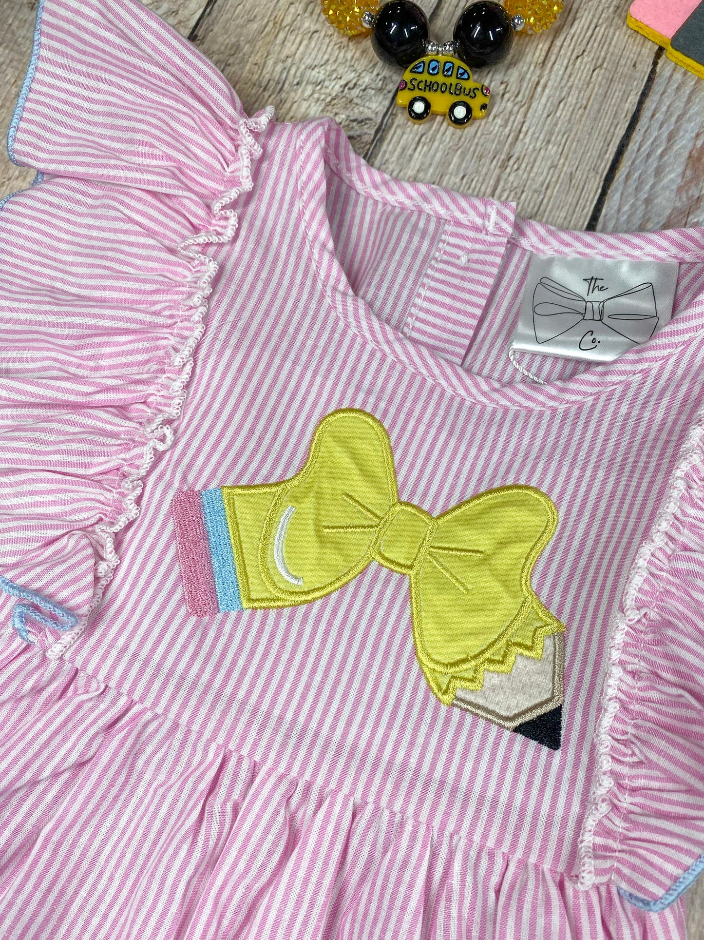 Pink dress with ruffled sleeves and blue shorts on a wooden background