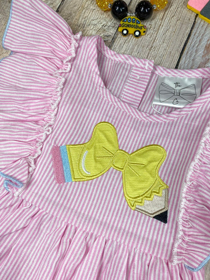 Pink dress with ruffled sleeves and blue shorts on a wooden background