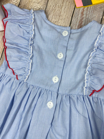 Children's outfit with blue top and pink shorts featuring an apple design on a wooden background