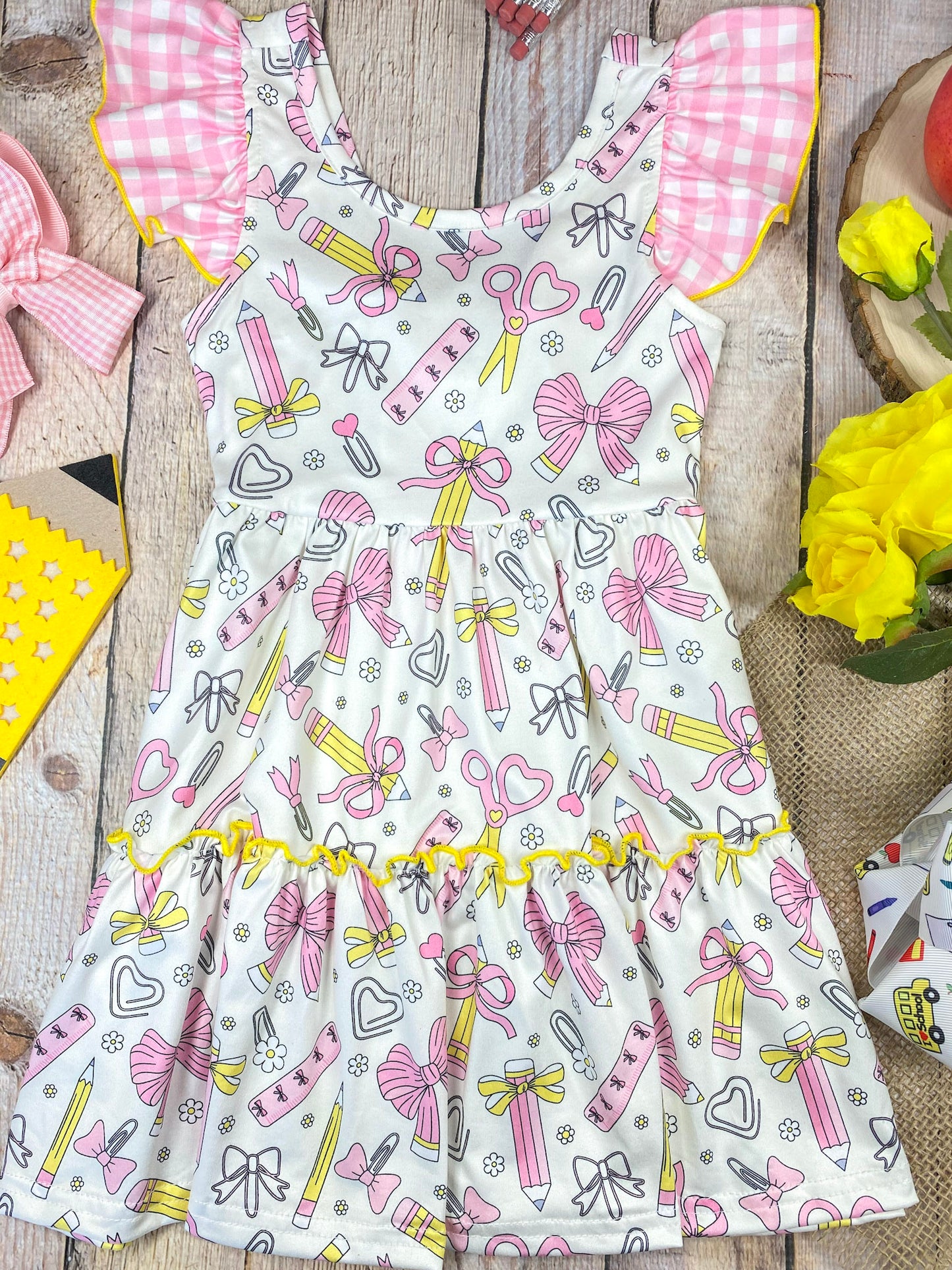 Children's dress with stationery-themed print on a wooden background