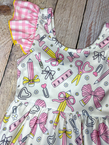 Children's dress with stationery-themed print on a wooden background