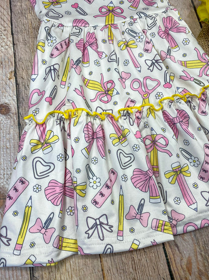 Children's dress with stationery-themed print on a wooden background
