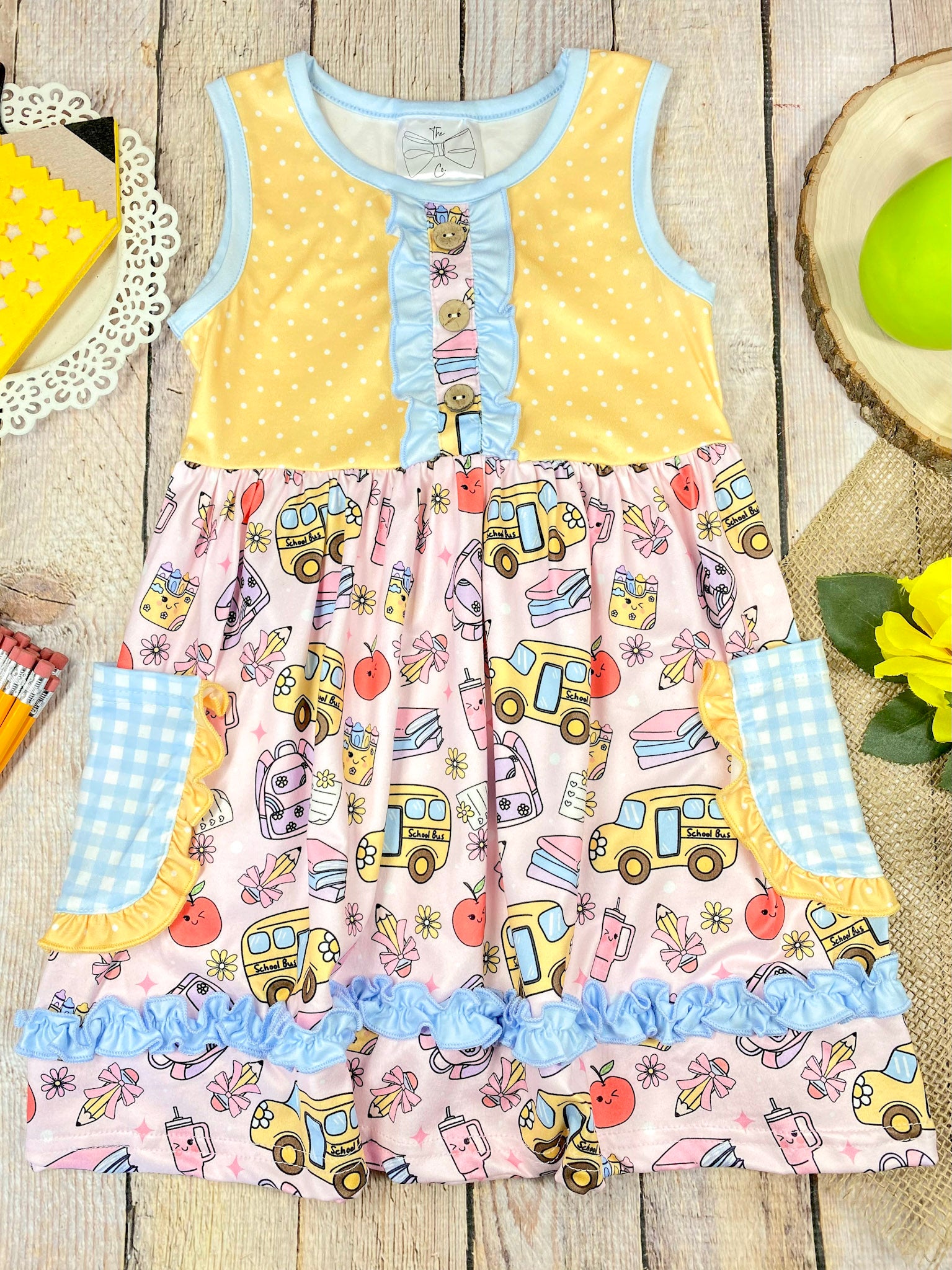Colorful children's dress with cartoon bus and apple pattern on a wooden background