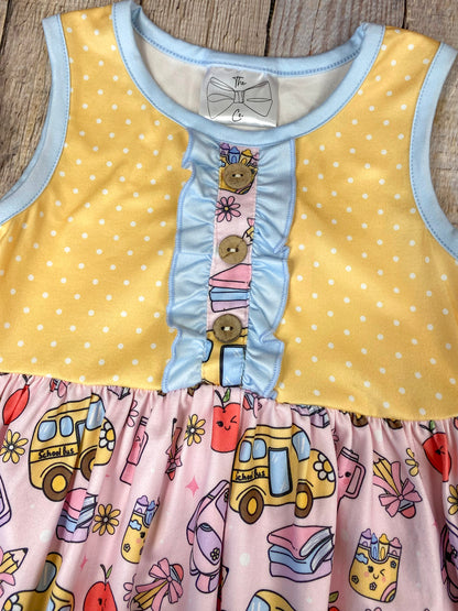 Colorful children's dress with cartoon bus and apple pattern on a wooden background