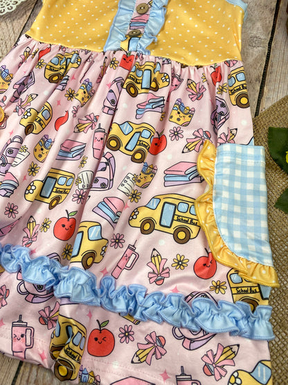 Colorful children's dress with cartoon bus and apple pattern on a wooden background