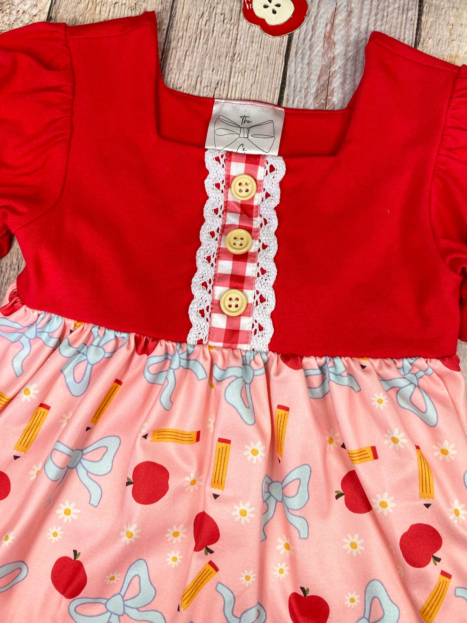 Red and pink children's outfit with checkered shorts on a wooden background