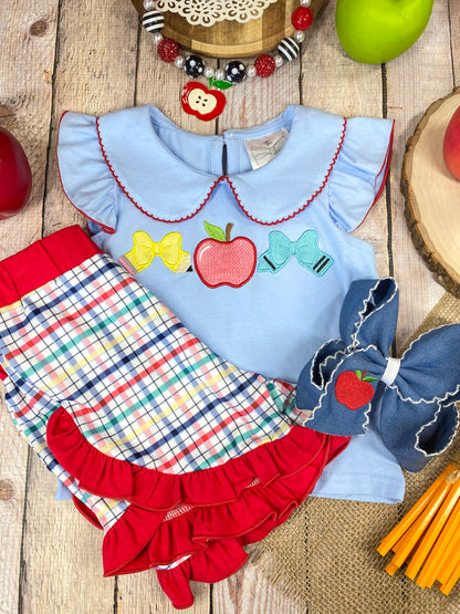 Children's outfit with light blue top and plaid shorts on a wooden background