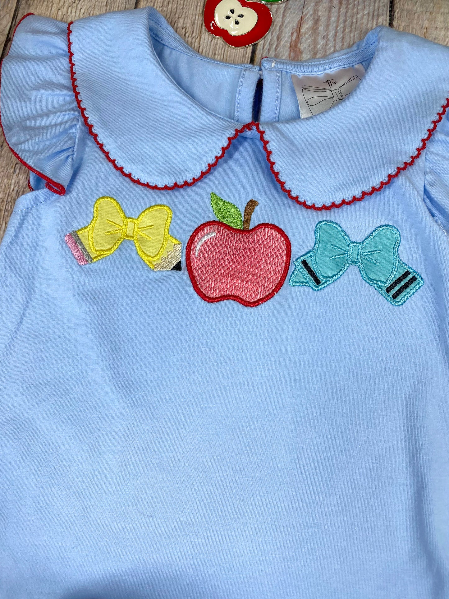 Children's outfit with light blue top on a wooden background