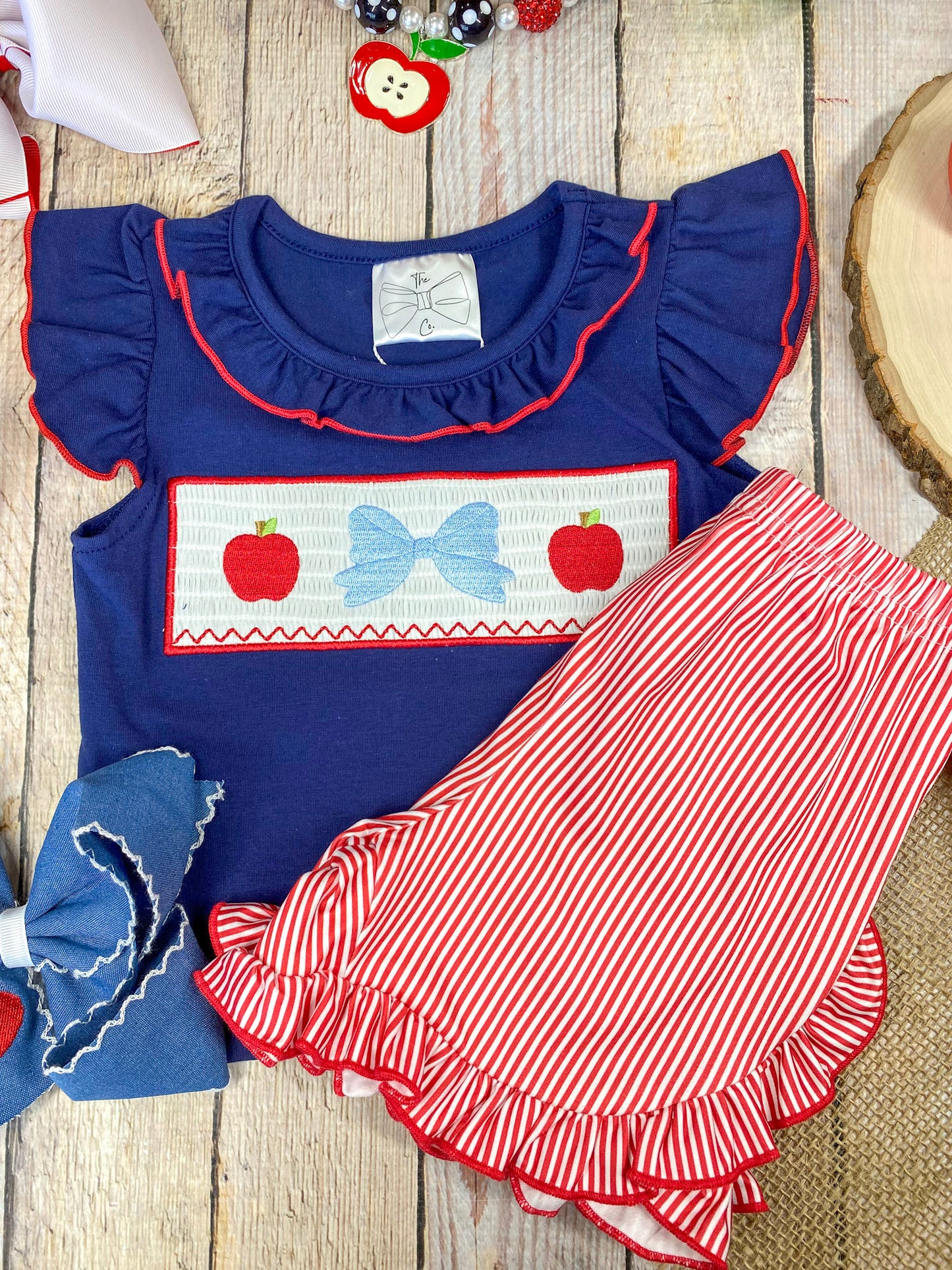 Navy top with red and white accents and red striped shorts on a wooden background