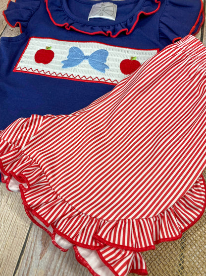Navy top with red and white accents and red striped shorts on a wooden background