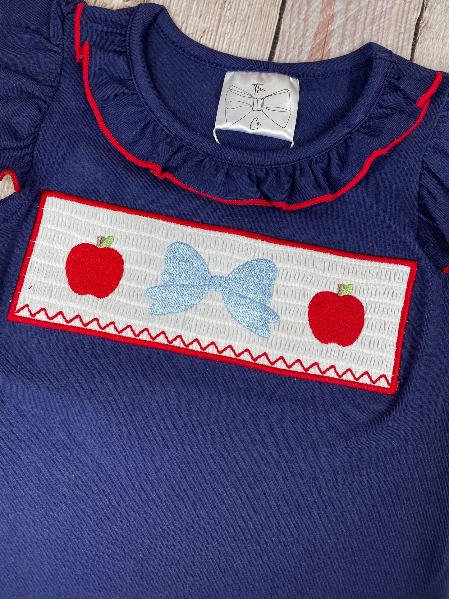 Navy top with red and white accents and red striped shorts on a wooden background