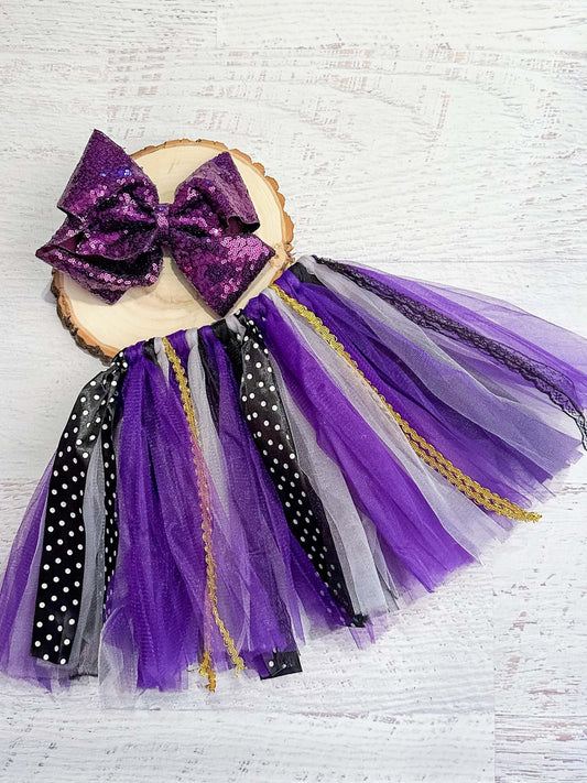 Tie tutu with purple, black, and white tulle strips, polka dot ribbon, black lace, and gold trim, with a striped bow at the front of the elastic waist.